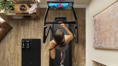 Peloton Tread Review: Pictured here, a fit woman running on a Peloton Tread indoors 