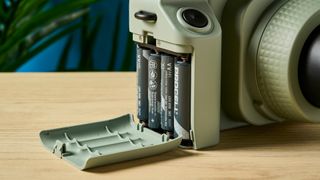 A sage green Fujifilm Instax Wide 400 instant camera