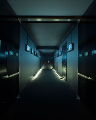Dark walls, rows of screens and sharp floor lighting give this corridor in the Aarhus head office the vibe of a futuristic spaceship