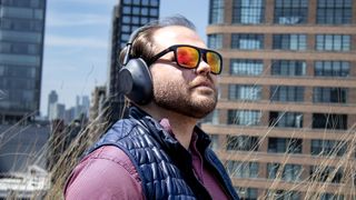 A man wearing black Sony WH-1000XM6 noise-cancelling headphones with sunglasses