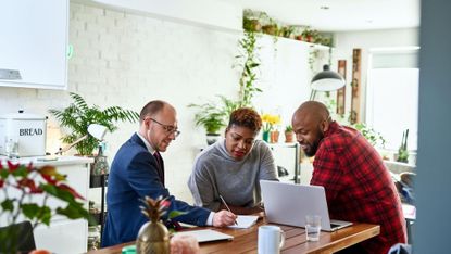 Couple listening to financial advisor at home with laptop