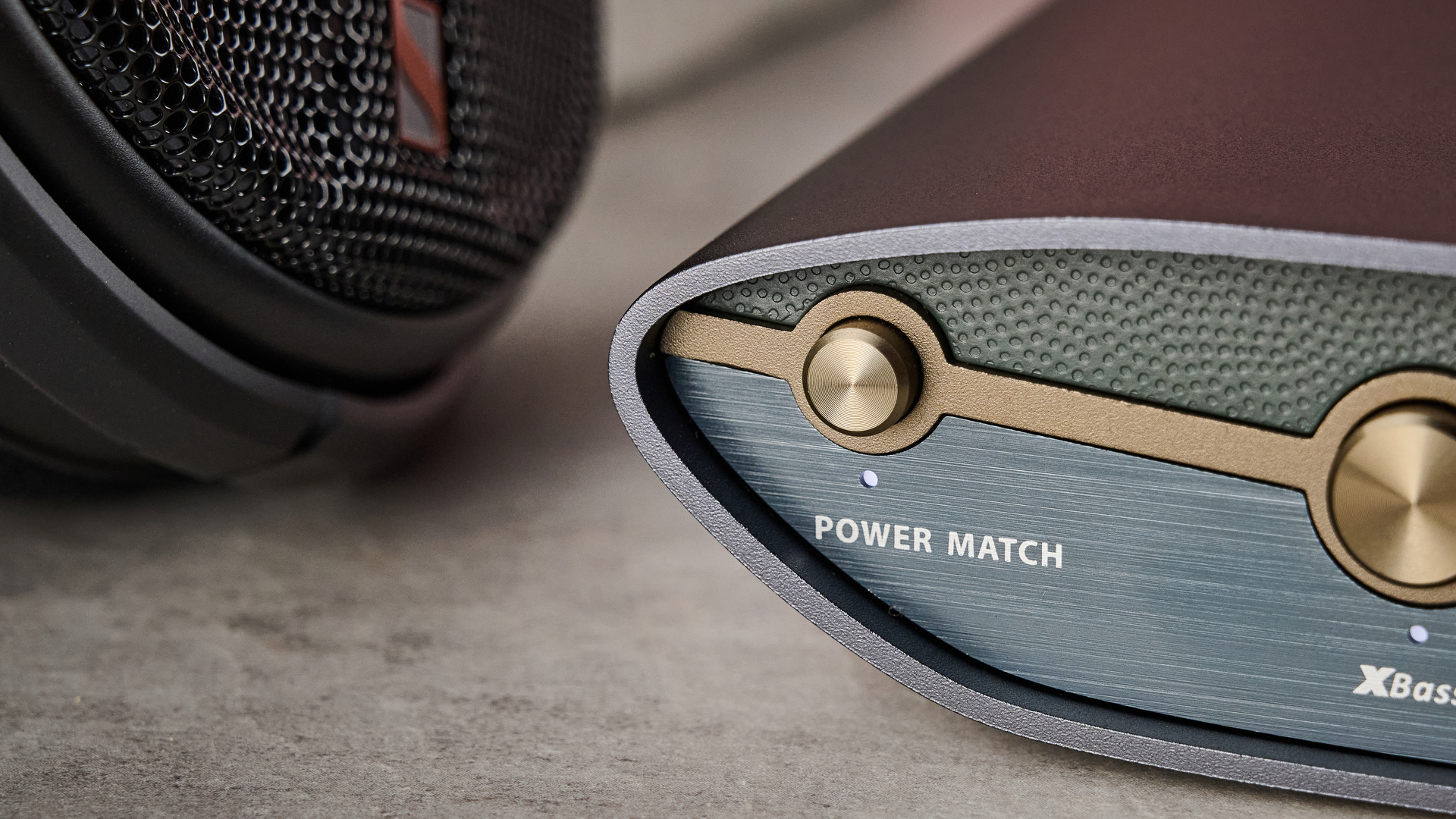 A closeup of the front of the iFi Zen DAC 3 and a corner of the Sennheiser HD 660S2 earcup.
