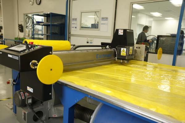 A vacuum pulls raw material down tightly against the surface of this table, where pieces are carefully cut using a computer-controlled blade.