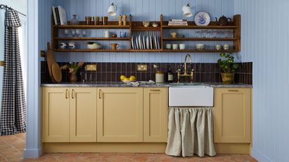 blue and yellow traditional kitchen with open shelving and sink skirt