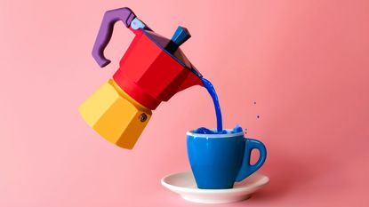 A colorful stovetop brewer pouring into a blue coffee cup