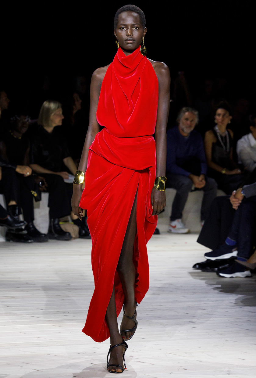 halter dress trend on the Alexander McQueen spring runway with a model wearing a red velvet dress styled with gold bangles and black sandals