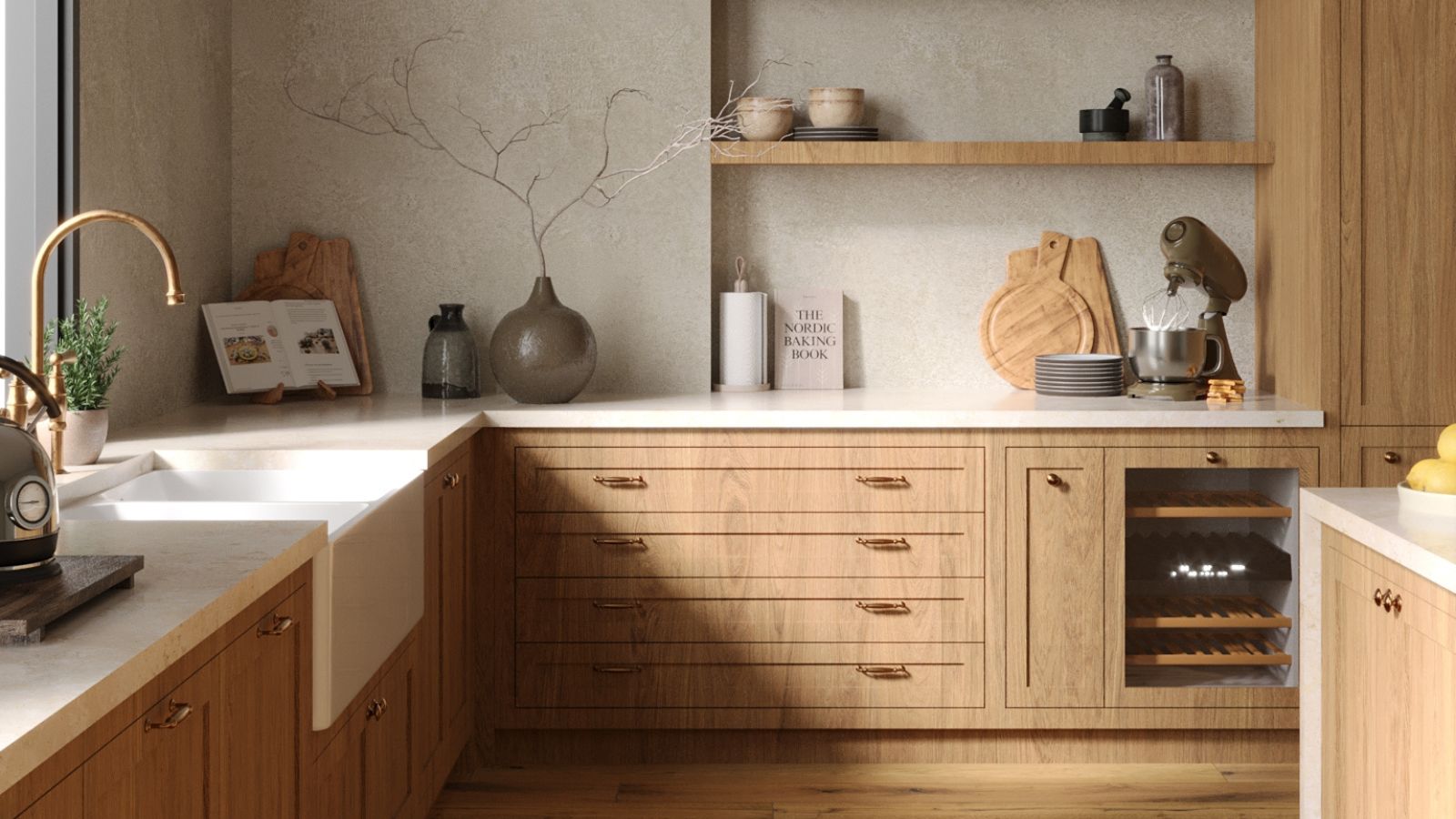 Warm wood kitchen with pale stone worktops, open shelving and brass handles. A deep white sink sits beside ceramics, cookbooks and a mixer.