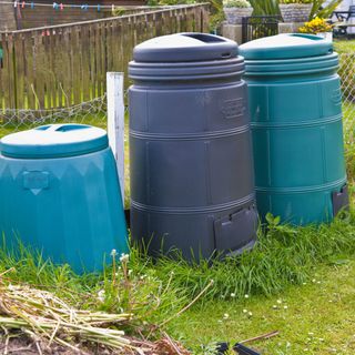 Three large plastic compost bins on grass lawn