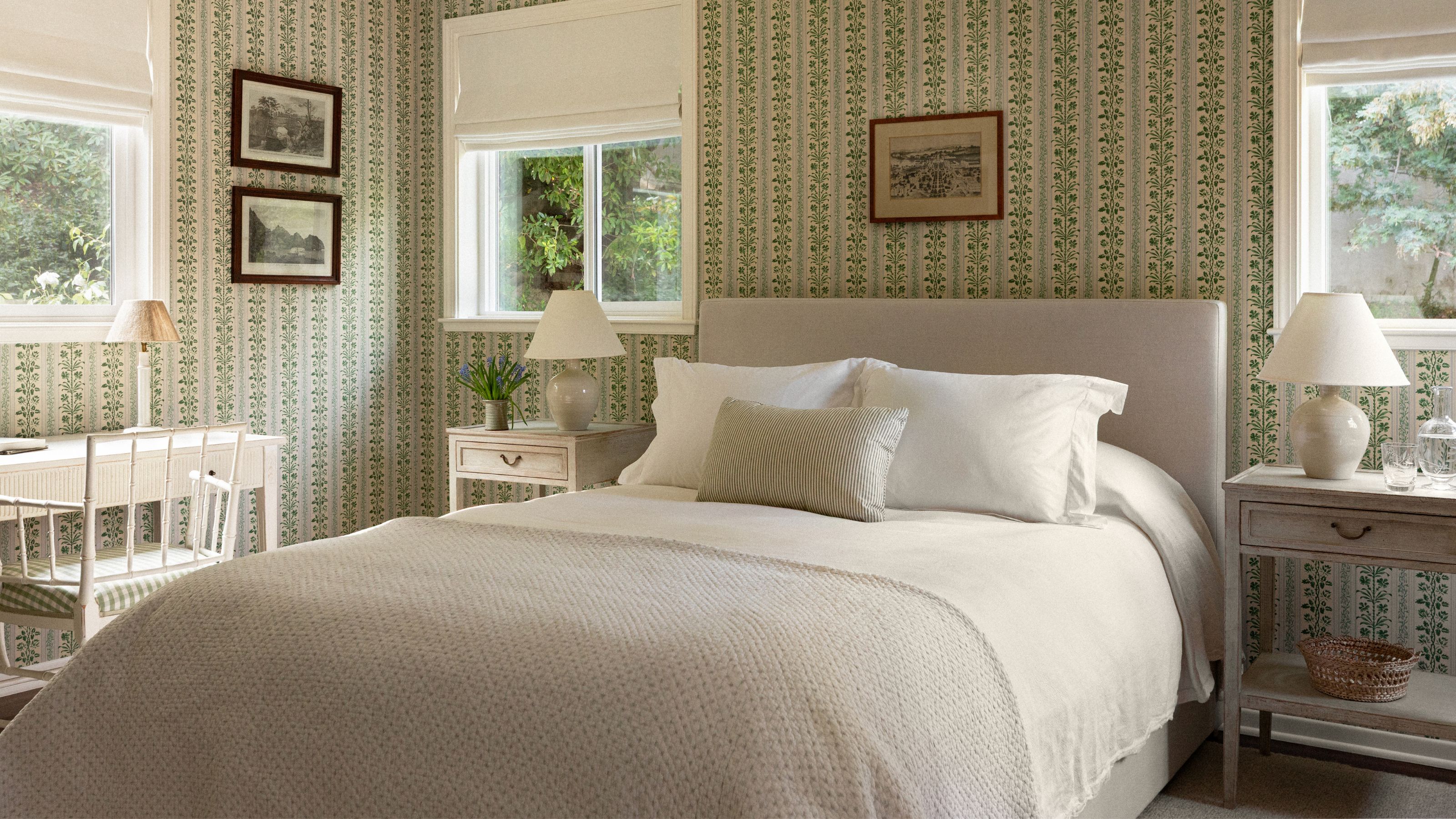 a floral wallpapered bedroom with three windows and a neutral dressed bed