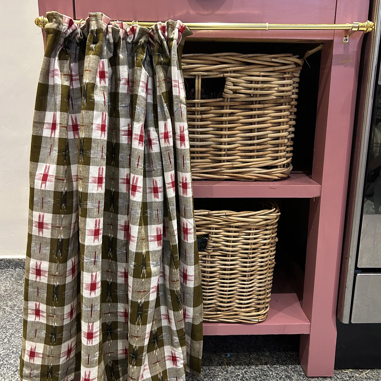 pink kitchen cabinet with patterned curtain across the front