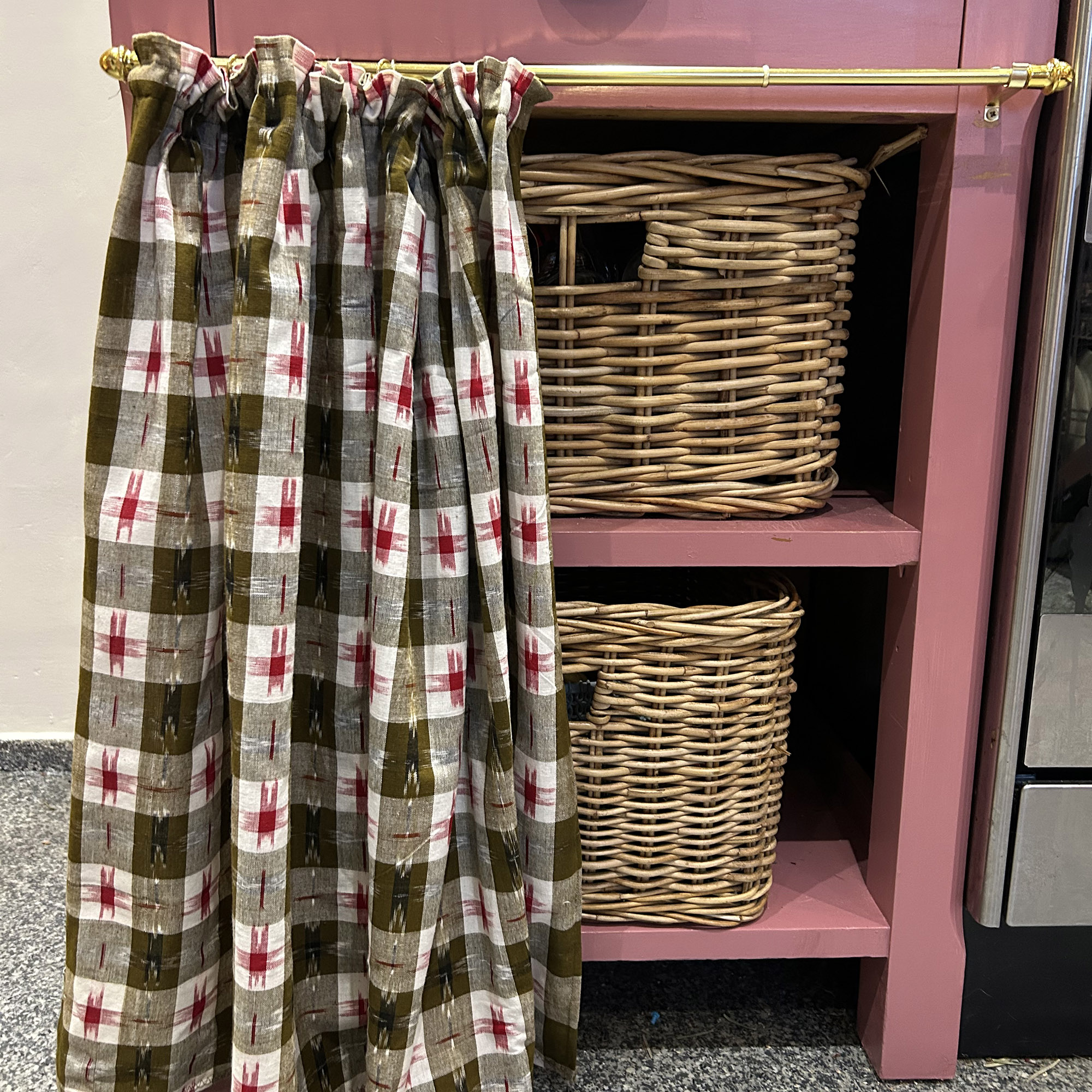 pink kitchen cabinet with patterned curtain across the front