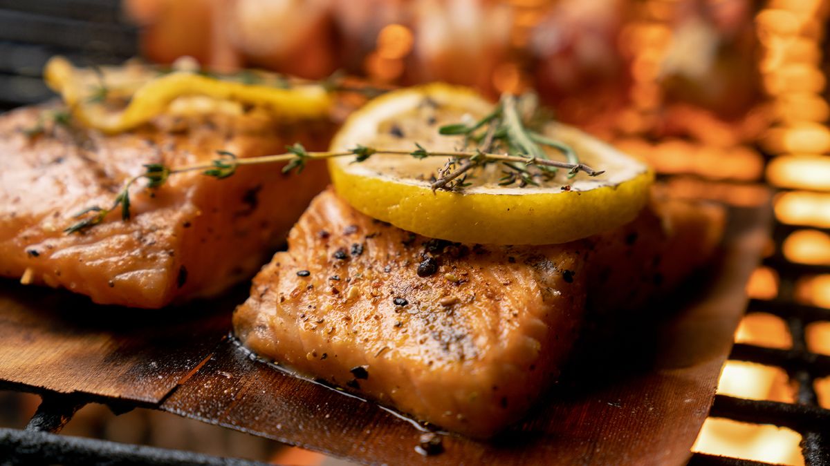 Salmon fillets seasoned and cooked on the grill with lemon slices and herbs