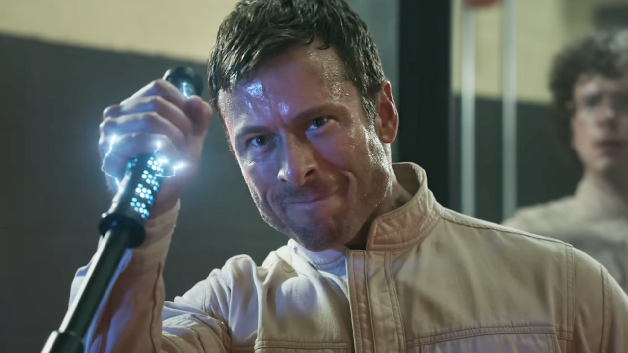 Glen Powell as Ben Richards, holding an electrocuting stick from The Running Man (2025).