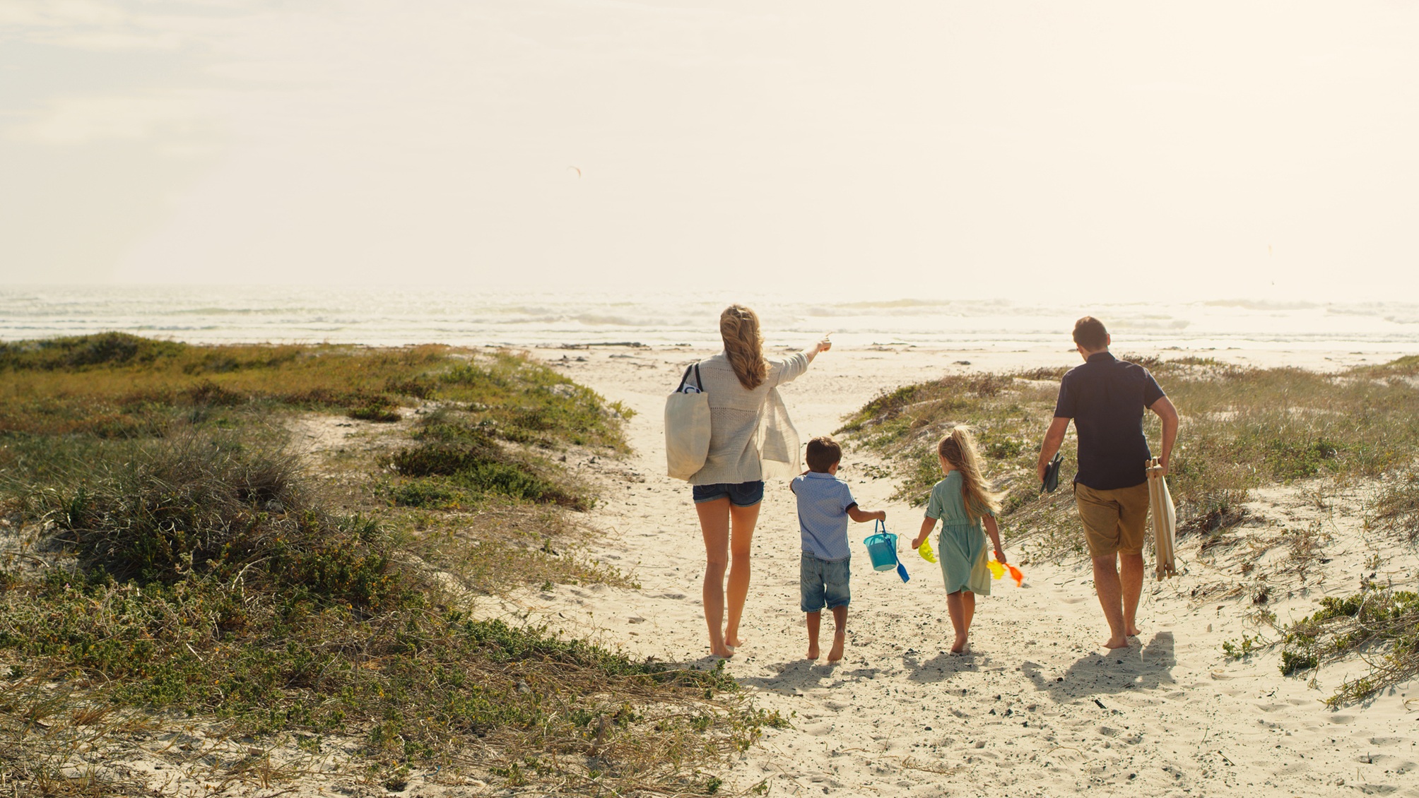 A family of four walks toward the beach.