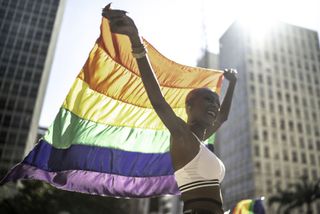 confident lesbian woman holding rainbow flag during pride parade
