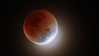 A total lunar eclipse or "blood moon" happening in the dark and quiet night sky in 2018.