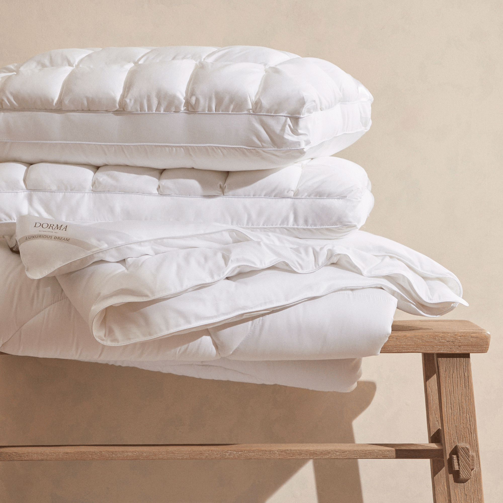 a stack of Dorma duvets and pillows from Dunelm on a wooden bench