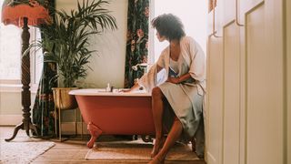 a woman drawing a bath in a standalone bath tub