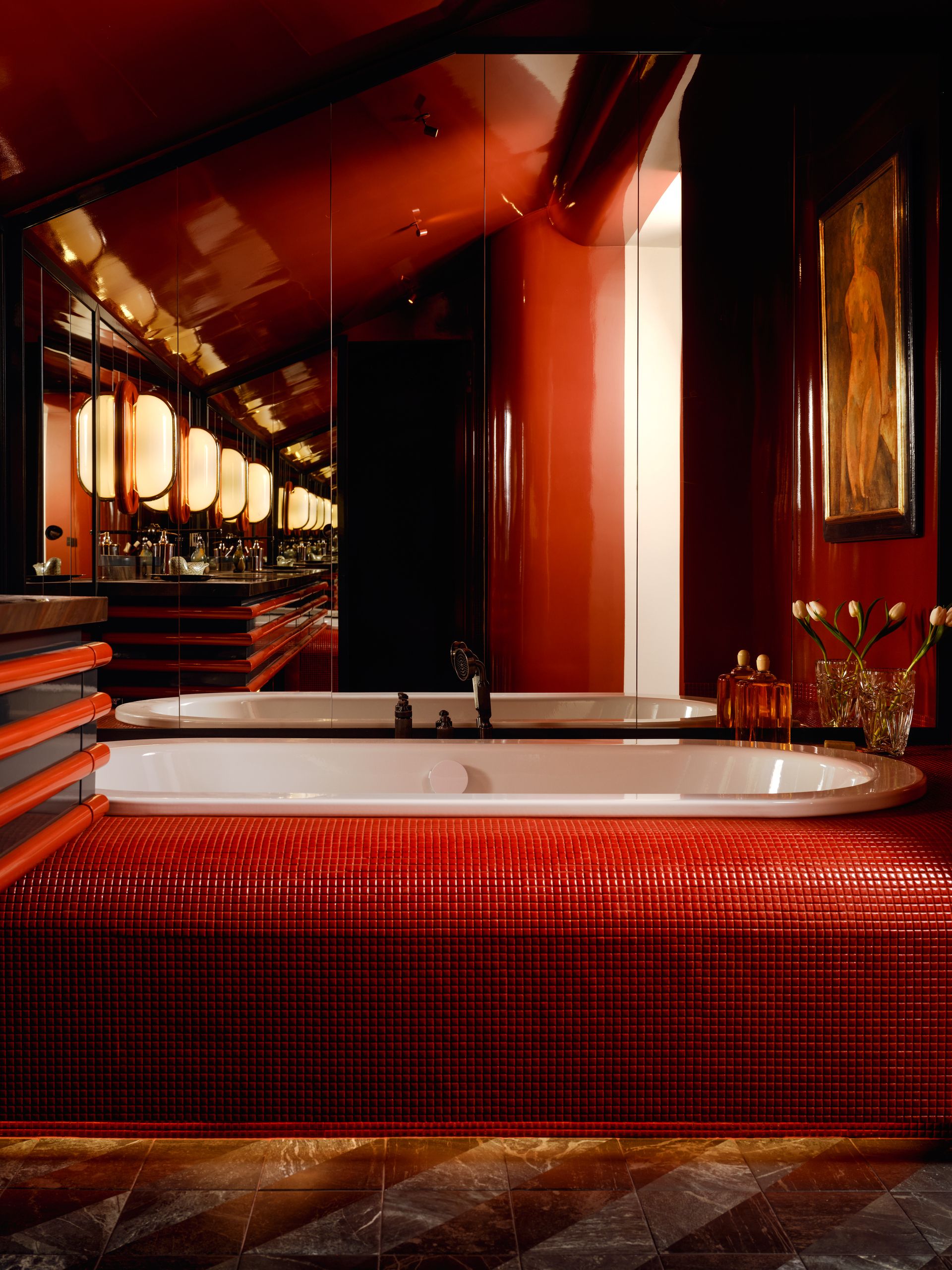 A color drenched red bathroom with a red mosaic tile tube, marble floors, and lacquered or mirror walls.
