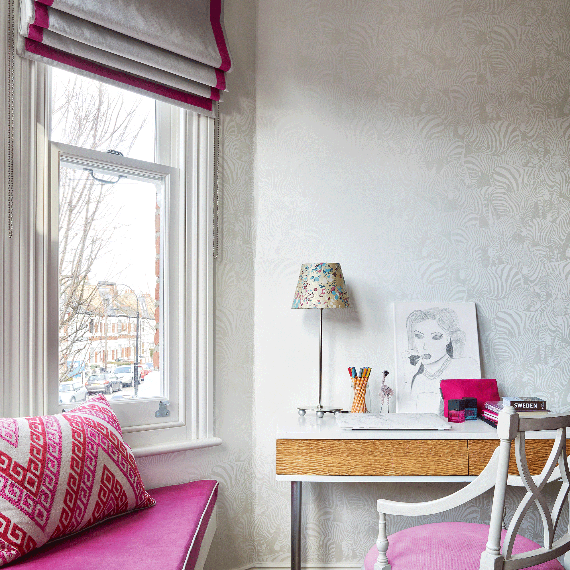White bedroom with a pink window seat and pink pattern cushion below a sash window