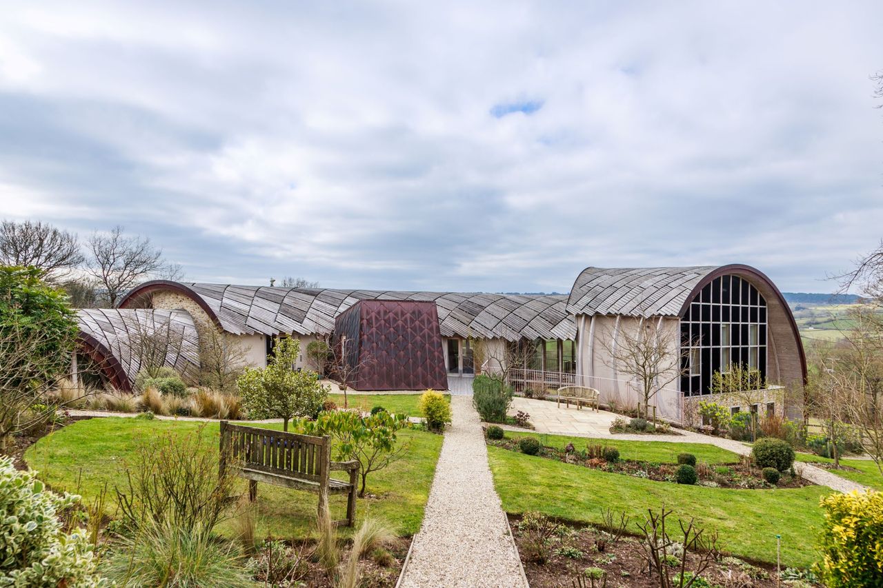 A front garden with stone walkway leading to a curved stone house