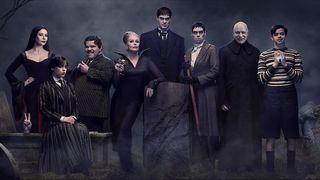 The cast of Wednesday posing in front of a gothic backdrop