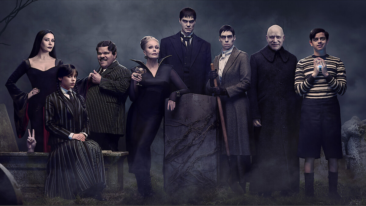 The cast of Wednesday posing in front of a gothic backdrop