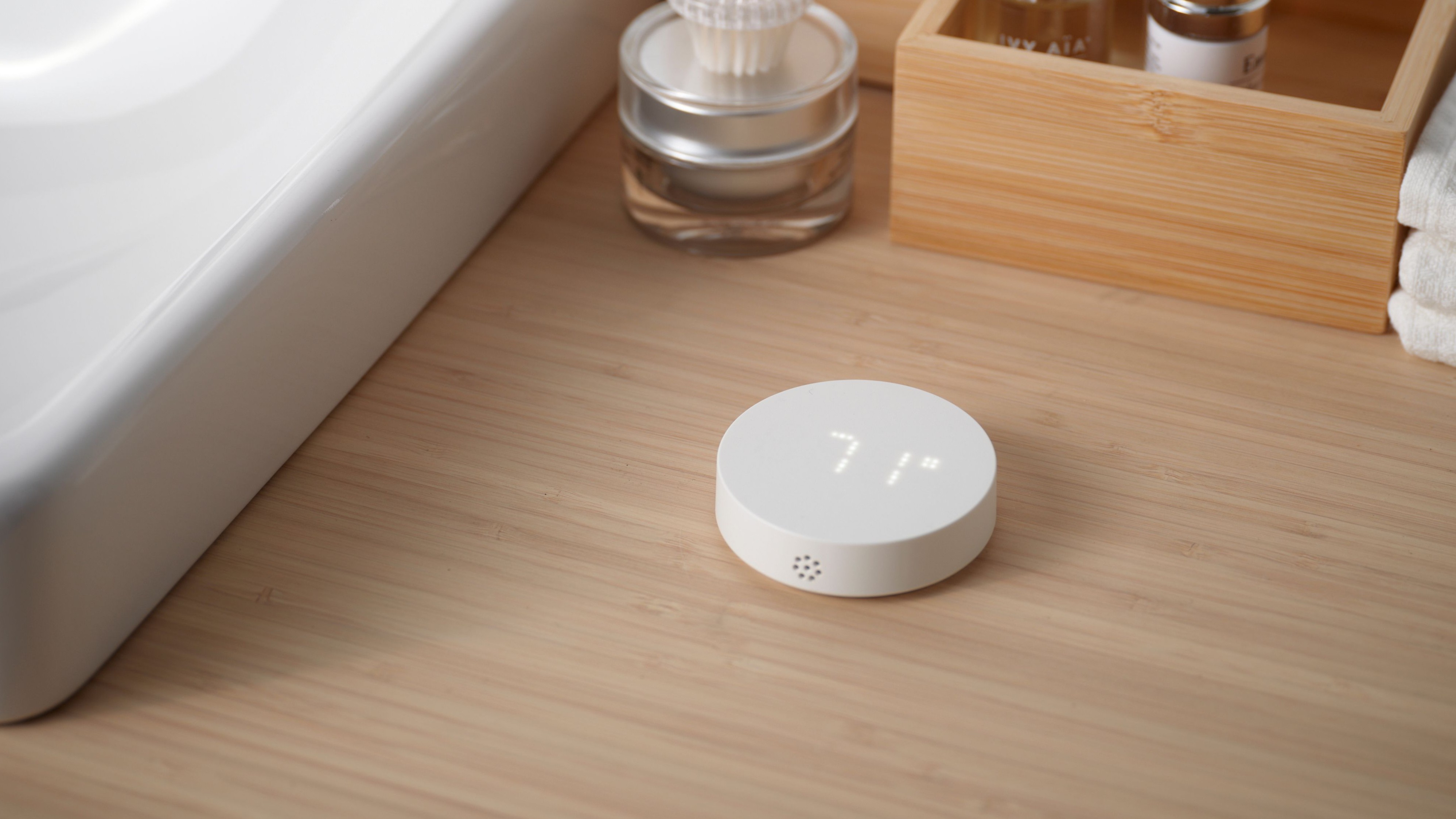 The Alpstuga air quality sensor on a bathroom counter top next to a sink basin