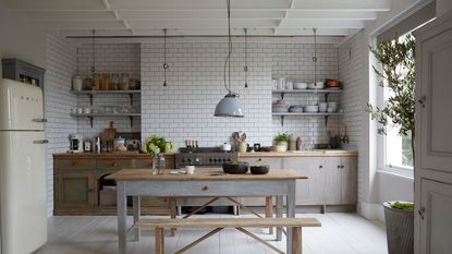 white tiled kitchen with open shelves and table