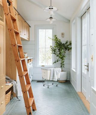 A light blue laundry room with a wooden ladder