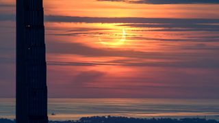 partial solar eclipse at sunrise through hazy cloud