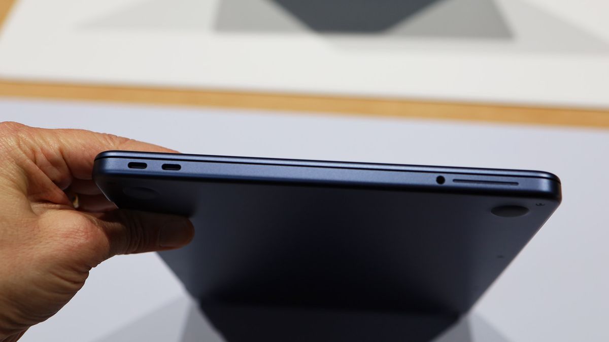 A hand holding the MacBook Neo showing its ports