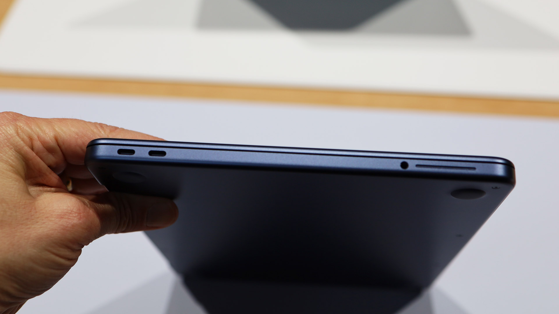 A hand holding the MacBook Neo showing its ports