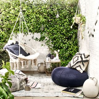 outdoor white brick wall plants white swing with cushion and book