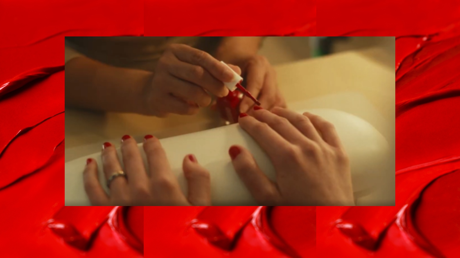 A red background with a still of a woman getting a red manicure