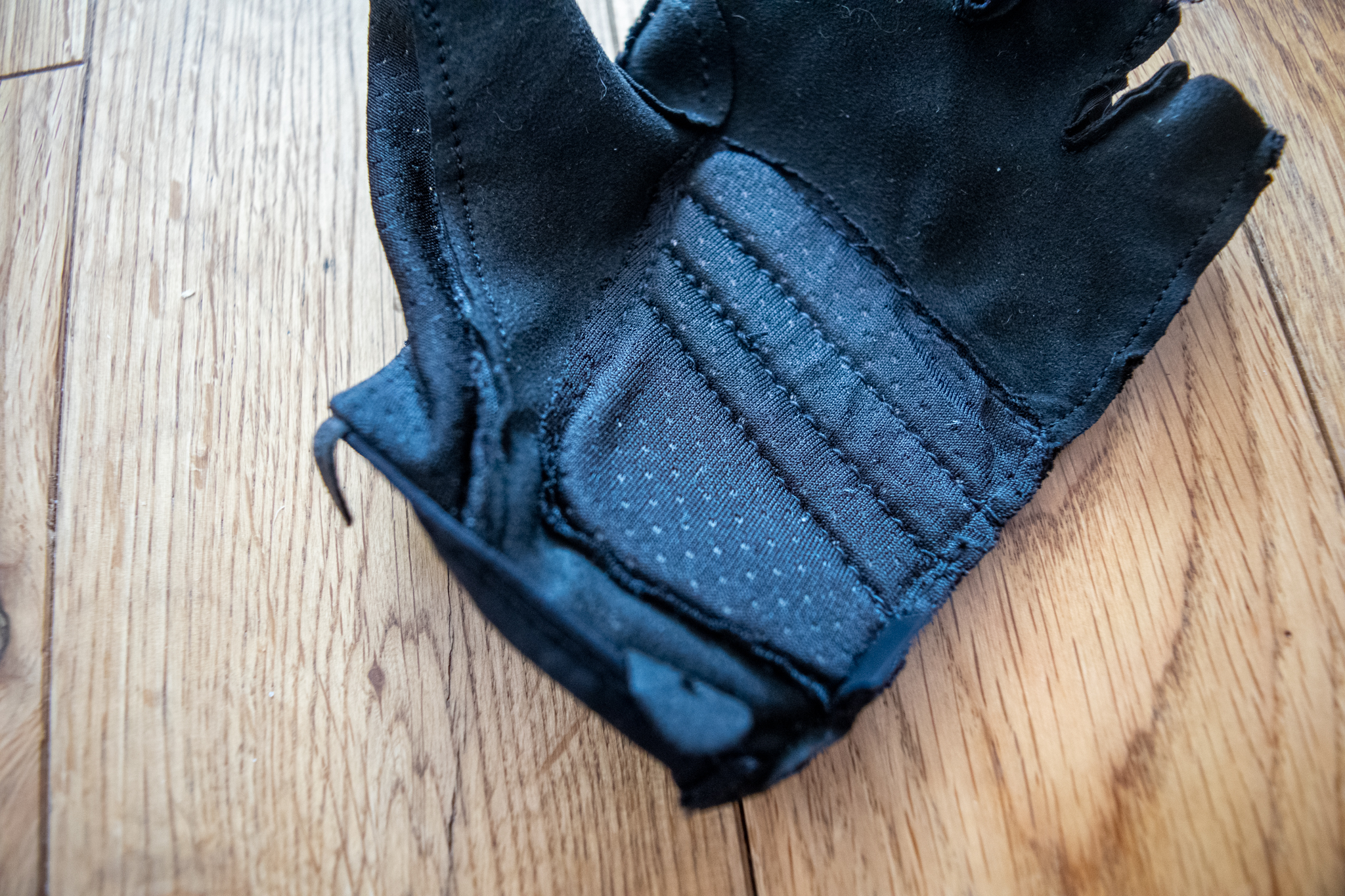 A black Rapha Core cycling mitt on a wooden floor