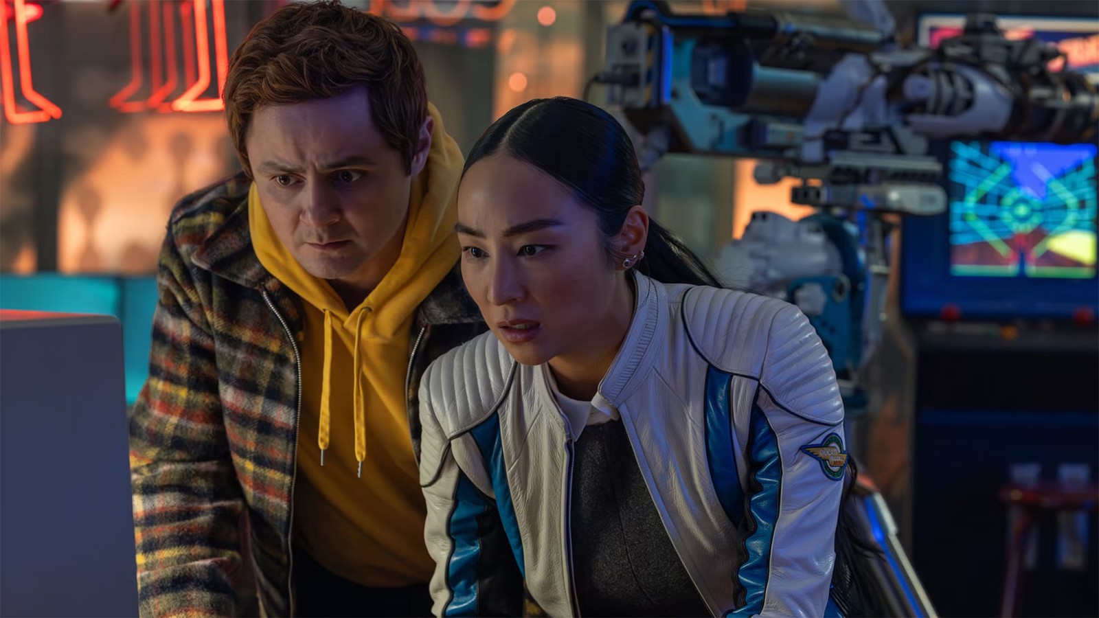Screenshot from the movie Tron: Ares. A man and woman and looking intently at a screen. In the background you can see lots of technical gear and screens.