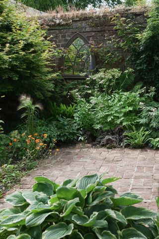 Shady area in the corner of a small garden with a mirror