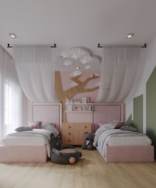 child's bedroom with 2 single white metal beds, white material draped on ceiling as canopies and wooden floor