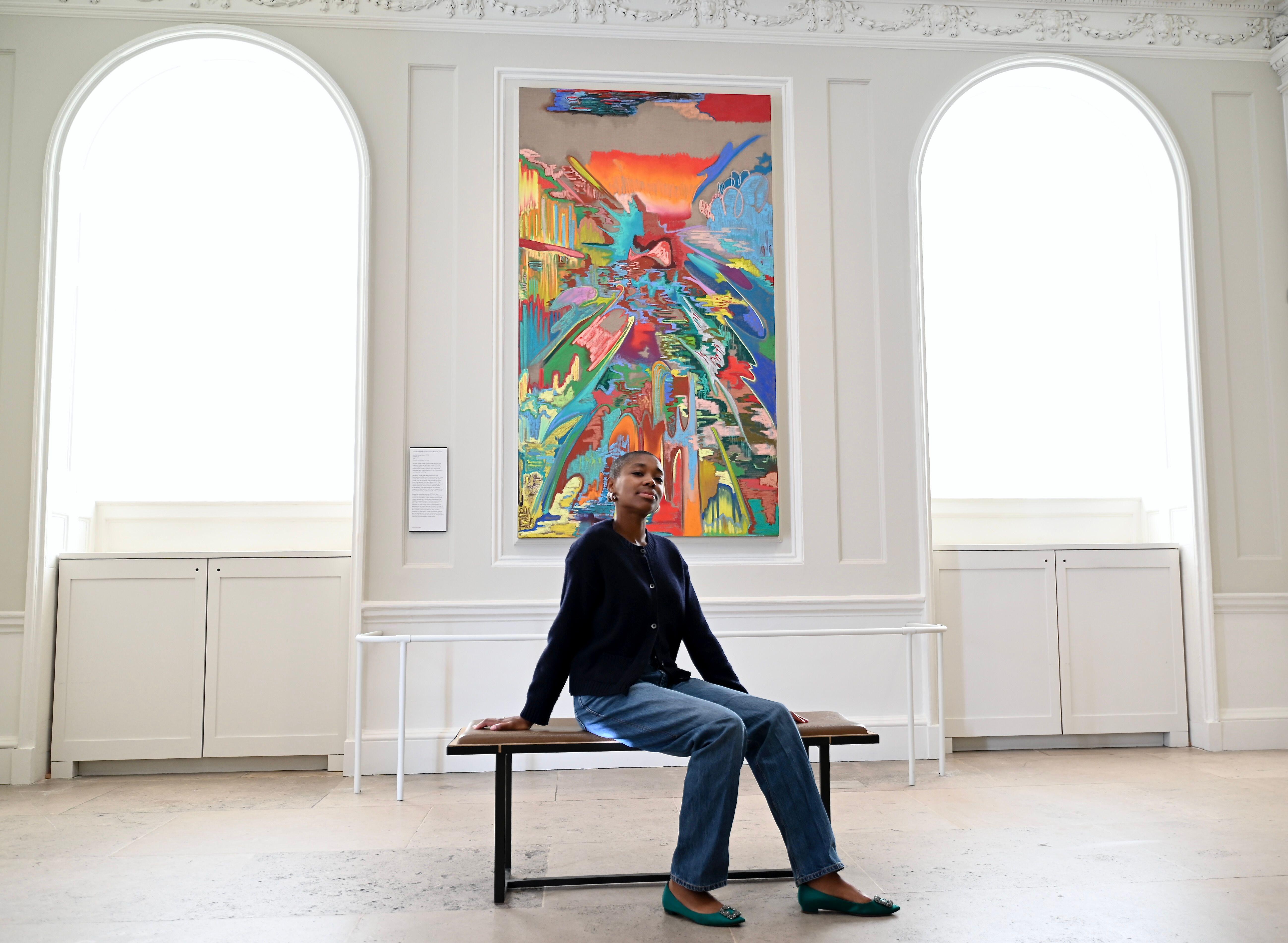 Rachel Jones sitting in front of one of her abstract artworks 