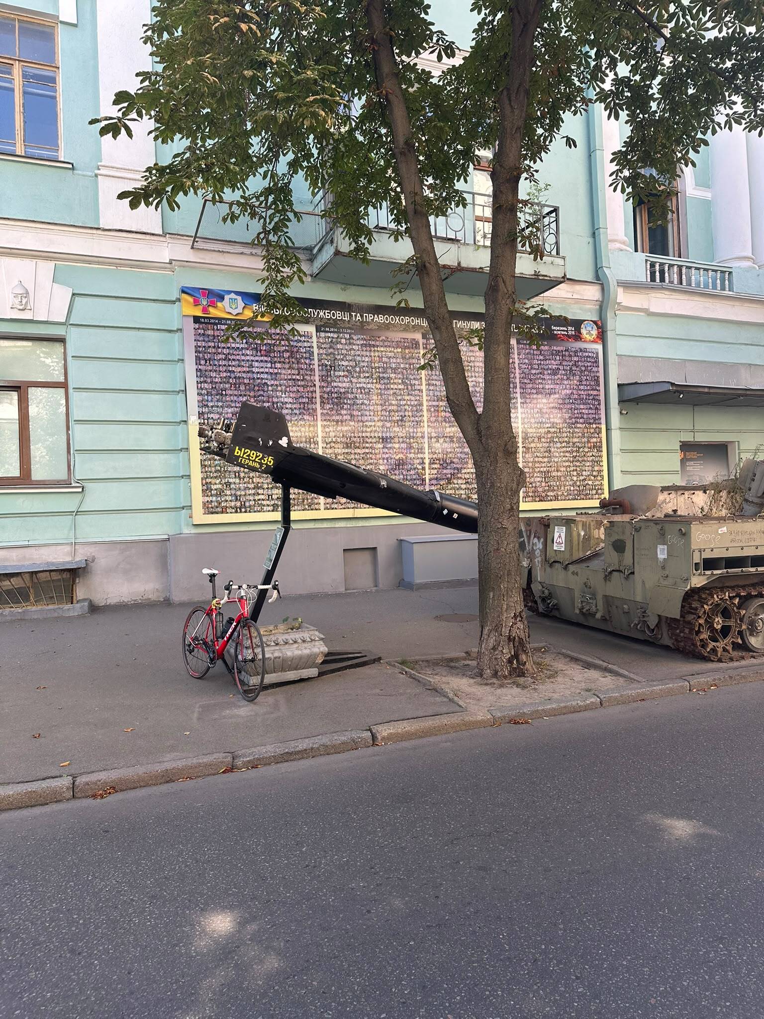 A bike sits in front of a tank on a city street