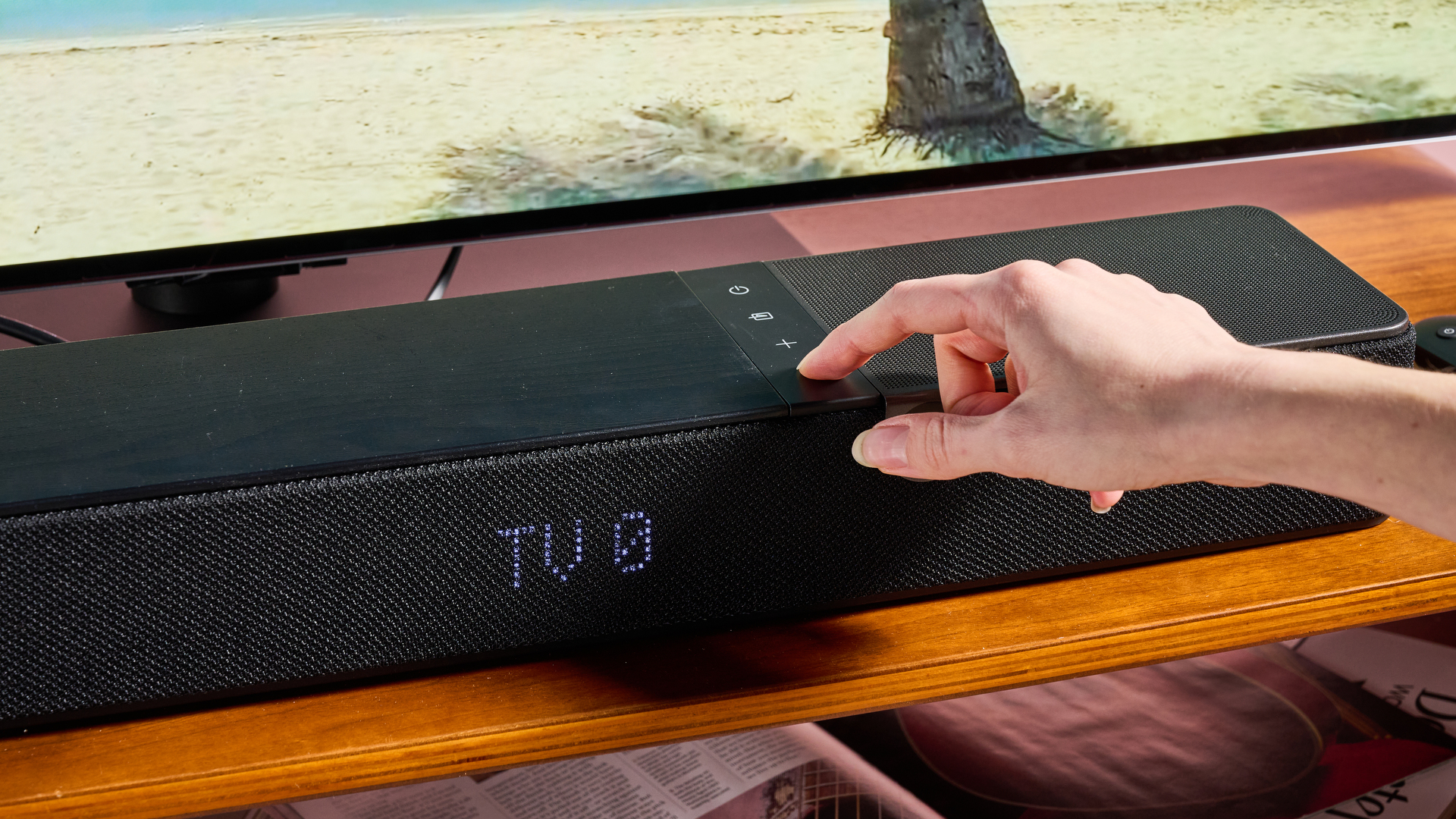 Person pressing button on the Klipsch Flexus Core 100