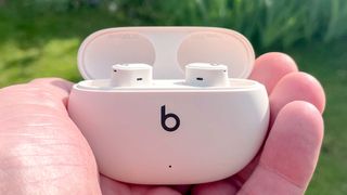 Beats Studio Buds+ in their charging case held in reviewer's hand in an outdoor setting
