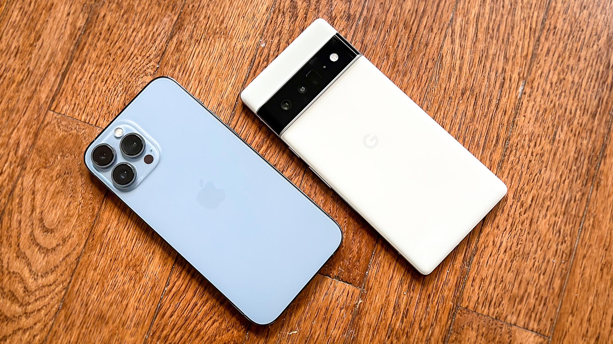 Pixel 6 Pro против iPhone 13 Pro Max: оба телефона лежат лицевой стороной вниз на деревянном полу