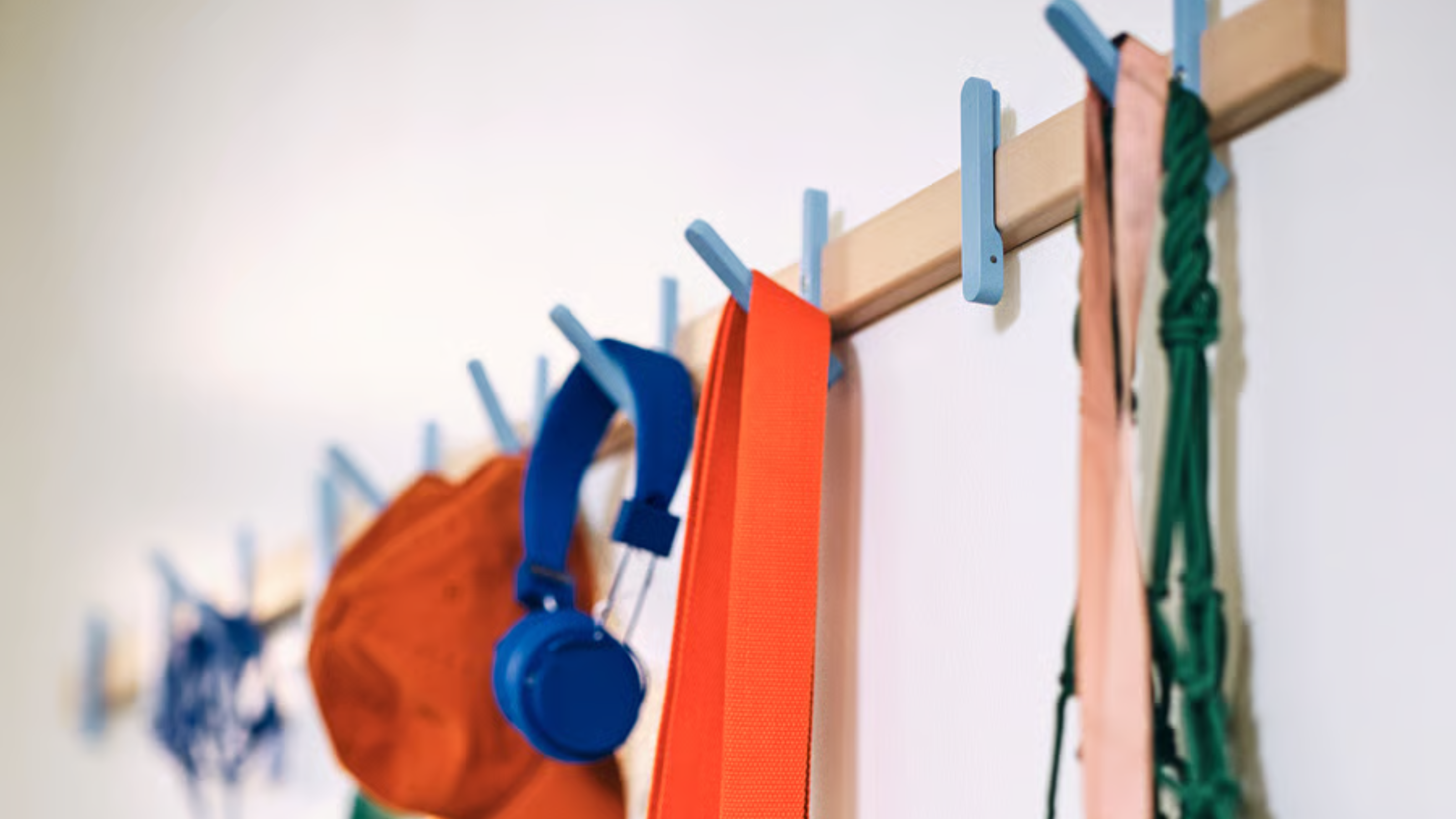 Close-up of the IKEA PS Rack with 5 hooks holding bags, headphones and hats.