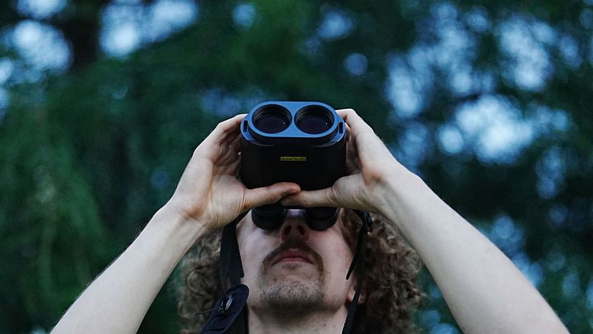 A man looking through the Fujifilm Techno-Stabi TS-L 1640 image-stabilized binoculars upwards with trees in the background.