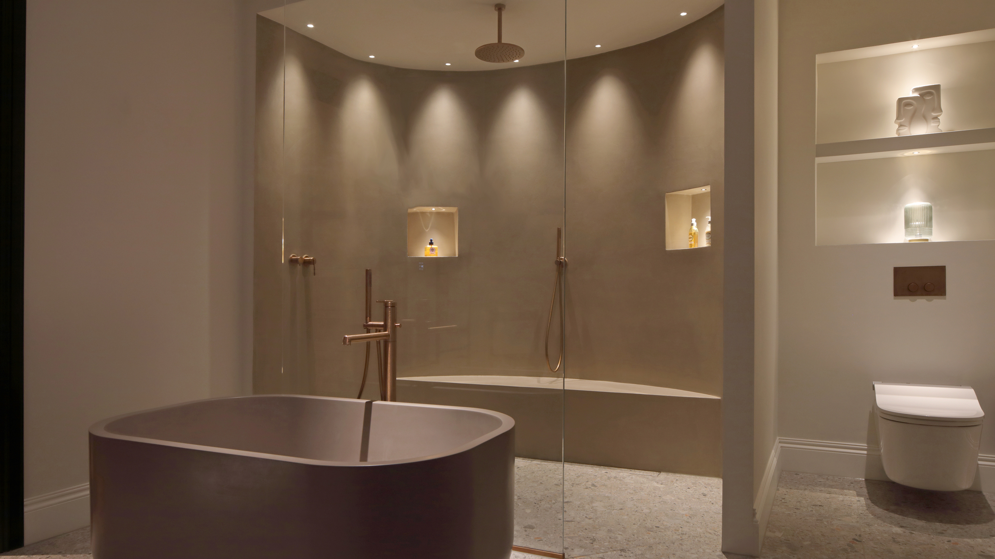 A bathroom with a freestanding tub and a walk-in shower in an alcove lit by spotlights