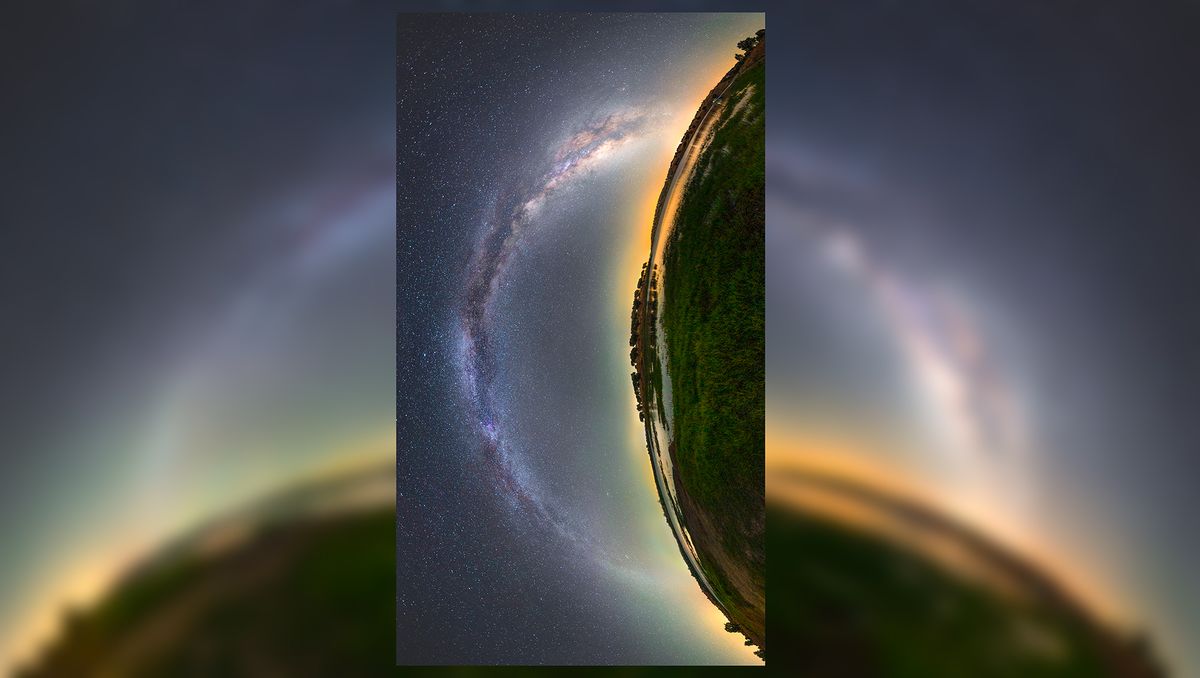 an arc of hazy white light stretches across a starry night sky next to a curved panoramic view of a lush green landscape. the whole image is rotated 90 degrees counterclockwise so that the sky is on the left and the landscape is on the right. the combination of the arc of white light and the arc of the ground forms almost an eye-like shape