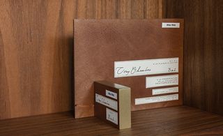 Card made from wood was stained toasty brown, edged in gold and affixed with a fabric label