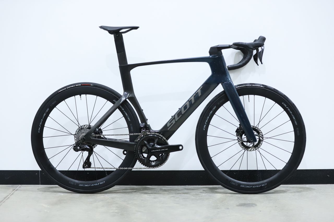 A blue Scott Foil RC Pro stands against a white wall